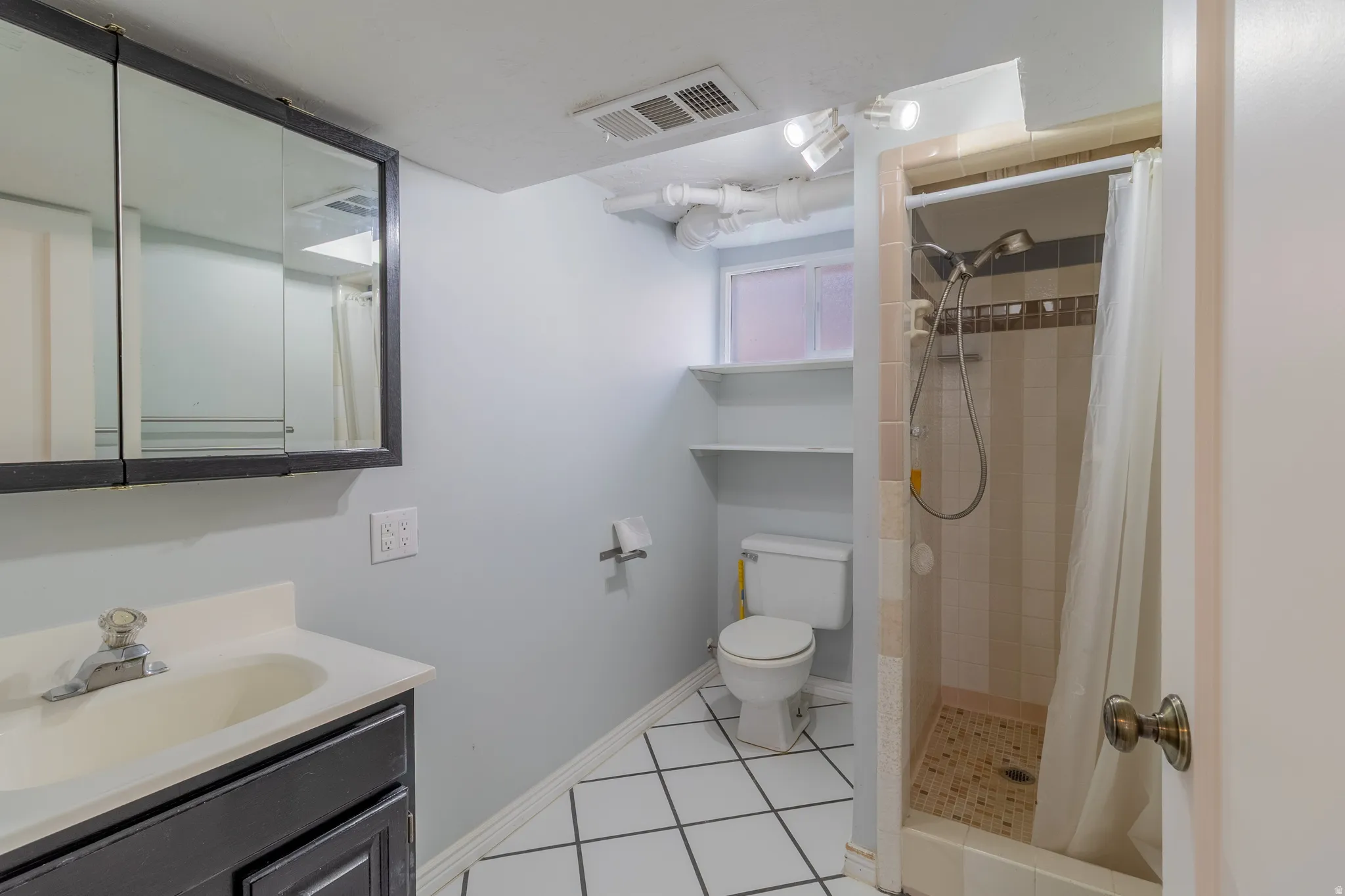 Full bathroom featuring a single vanity, wall-mounted medicine cabinet, toilet, and a shower with tiled walls