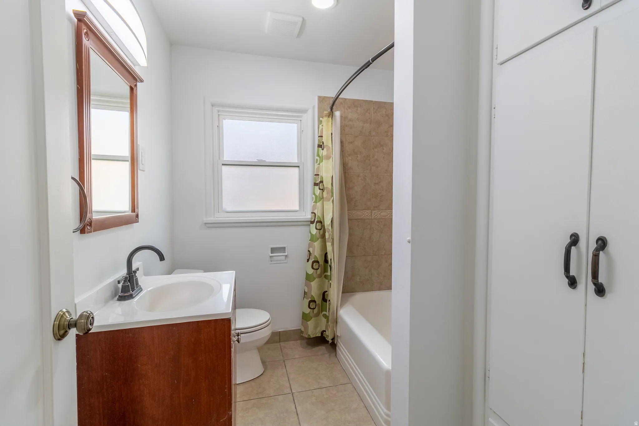 Bathroom featuring a wood-finish vanity with an integrated sink, a full bathtub with tiled surround, and built-in storage cabinetry