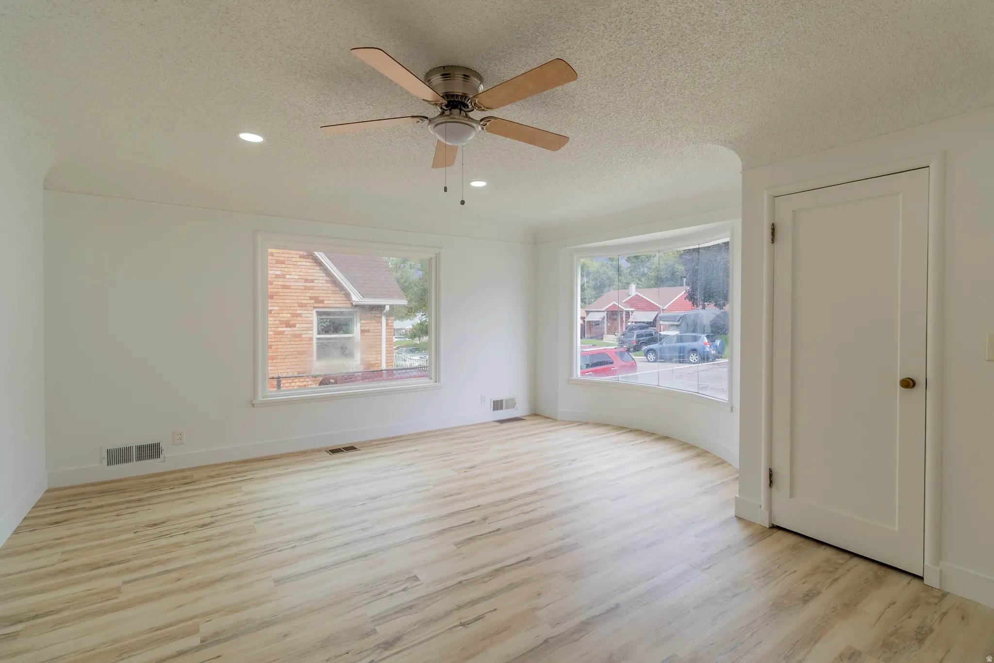 Wood-finish flooring, recessed lighting, ceiling fan, and large windows with white trim