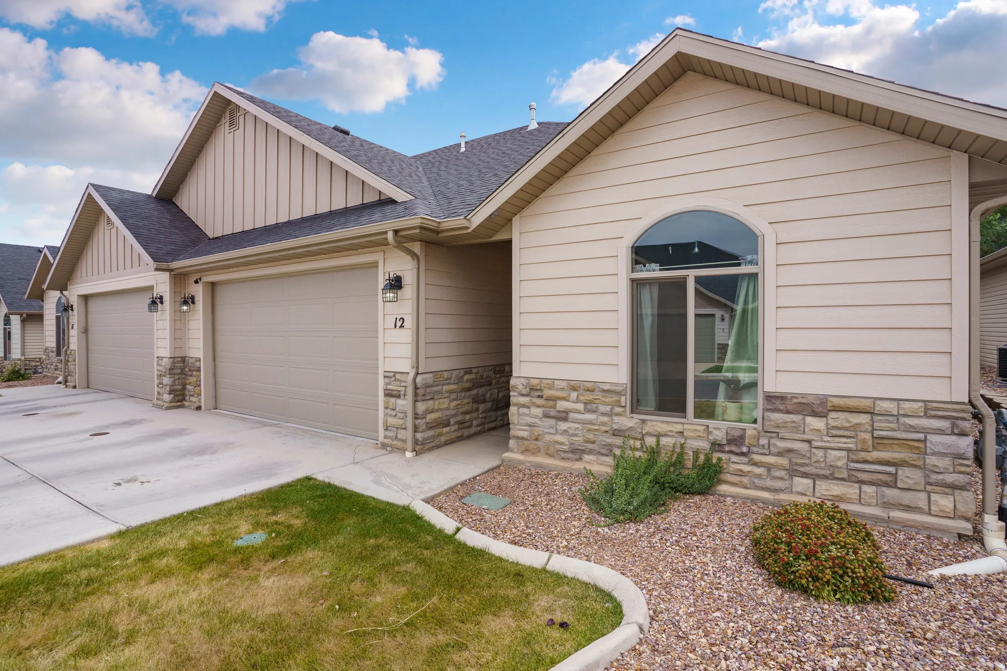 Exterior featuring horizontal siding, stone facade, a two-car garage, and an arched window