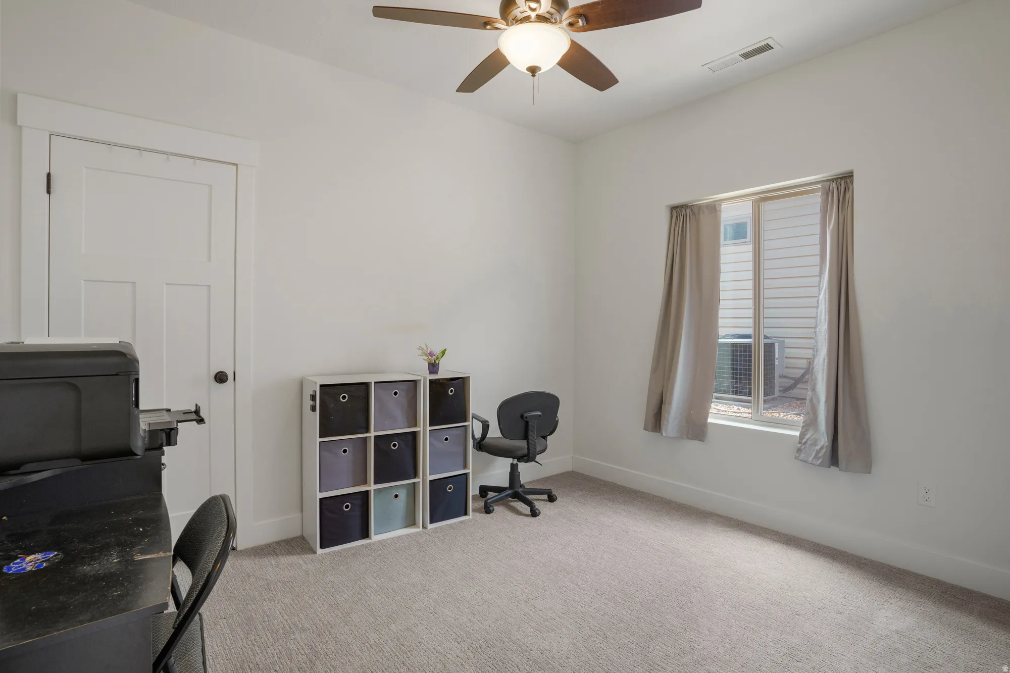 Recessed window with full curtains, ceiling fan with integrated lighting, and neutral carpeting