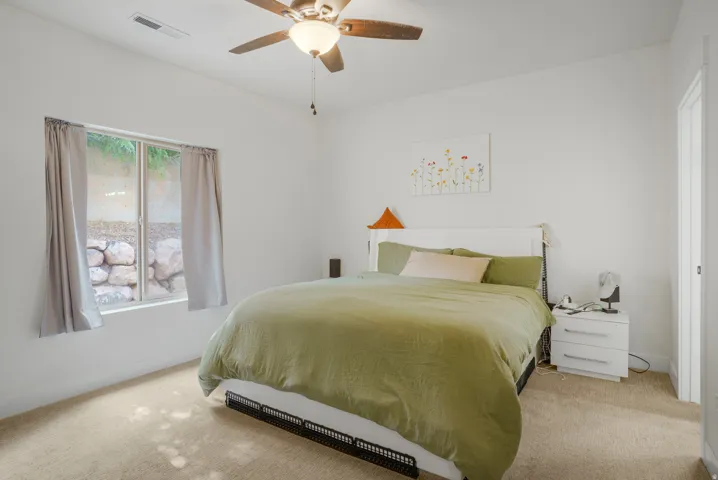Carpeted flooring, white walls, and a ceiling fan with integrated lighting