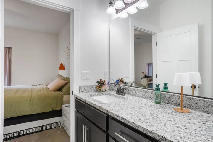 Granite-finish countertop with an integrated sink, dark wood-finish cabinetry, and a wall-mounted mirror