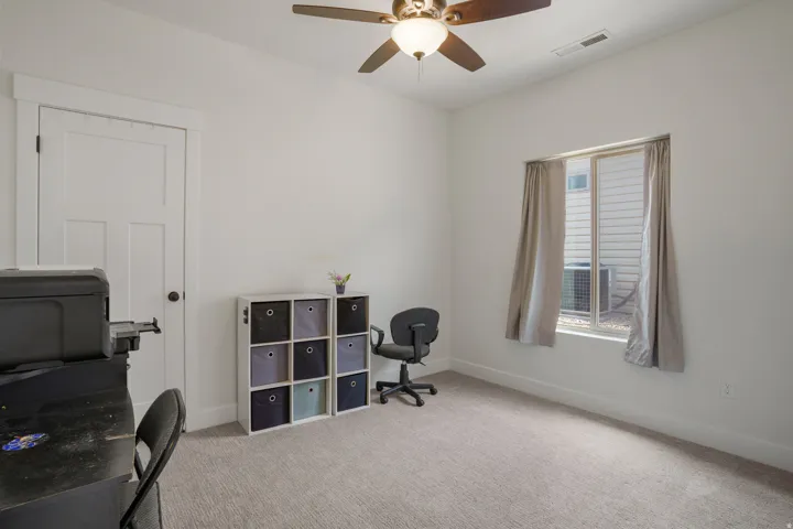 Recessed window with full curtains, ceiling fan with integrated lighting, and neutral carpeting