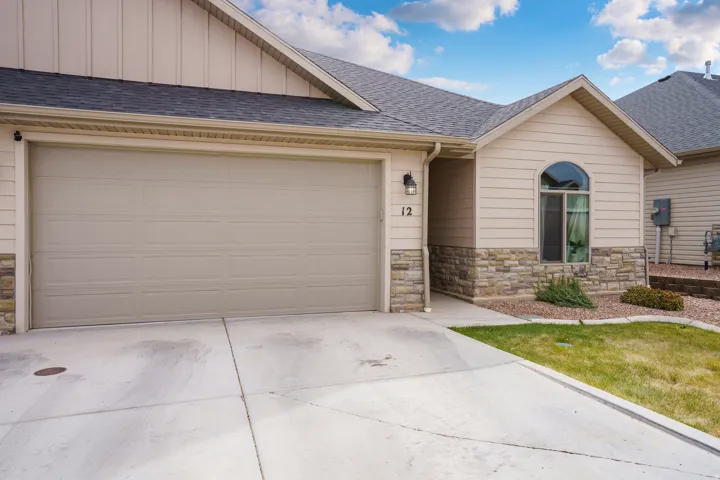 Attached two-car garage, stone and siding exterior, arched window, and concrete driveway