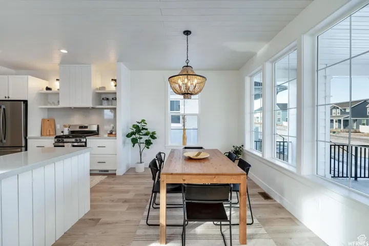 Open-concept living space featuring a modern kitchen, wood-finish flooring, white shiplap ceiling, and abundant natural light from multiple windows
