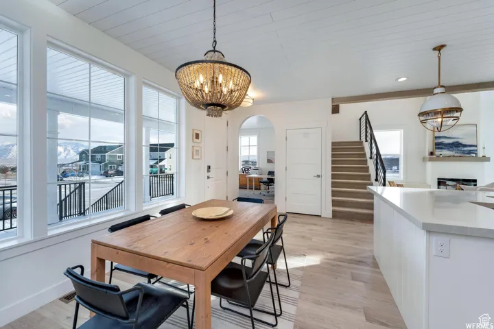 Open-concept living space with wood-finish flooring, a contemporary beaded chandelier, and a shiplap ceiling