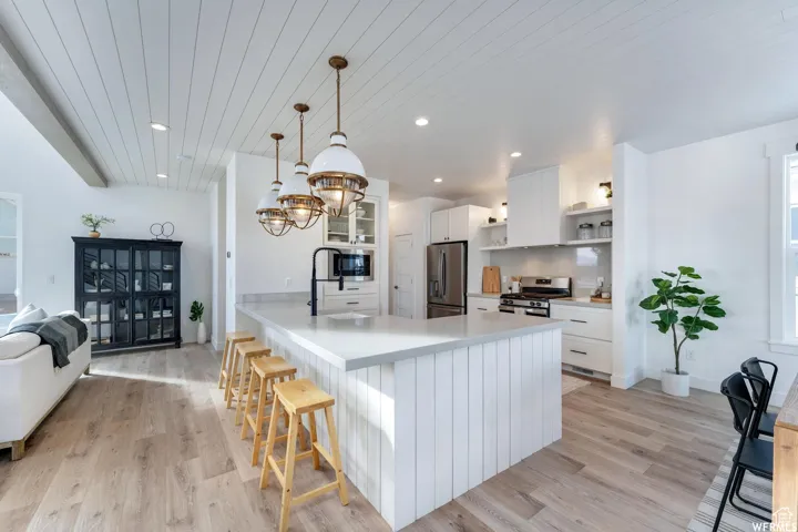 Open-concept kitchen with plank ceiling, recessed lighting, a center island, stainless steel appliances, and wood-finish flooring