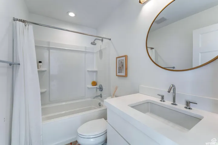 White vanity with an integrated rectangular sink, chrome fixtures, and a circular mirror