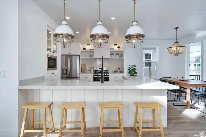 Kitchen featuring a large island with white shiplap base, integrated stainless steel appliances, white cabinetry, and recessed lighting