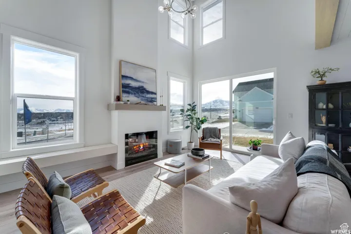 Soaring ceilings with upper-level windows, gas fireplace, and wood-finish flooring