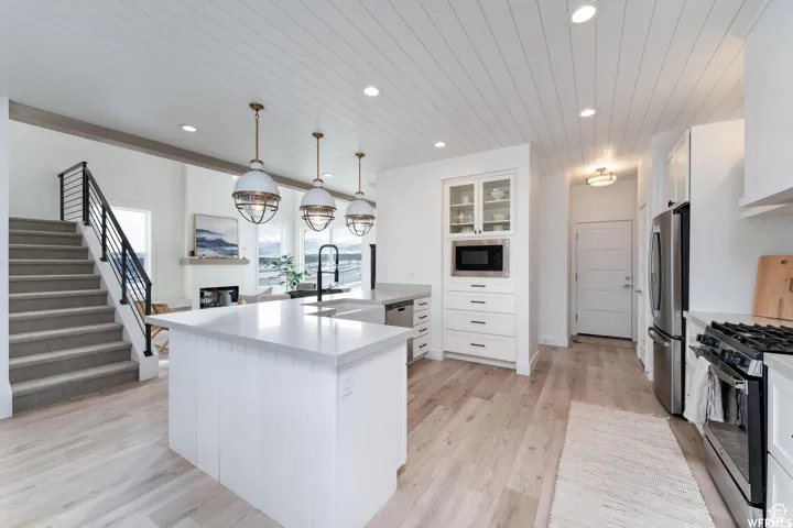 Kitchen with a center island, pendant lighting, wood-finish flooring, and stainless steel appliances