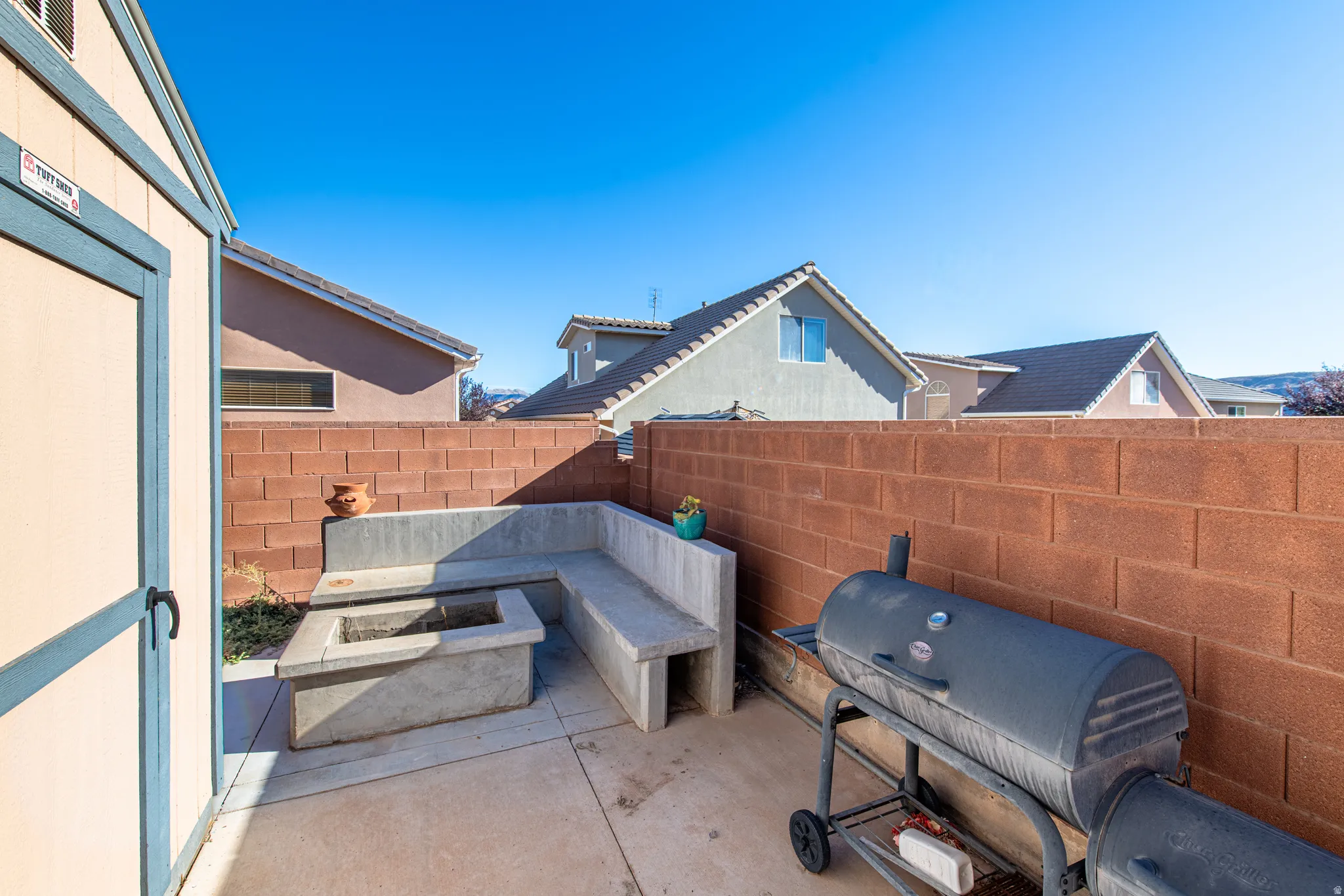 Paved patio featuring a built-in concrete bench and an integrated fire pit