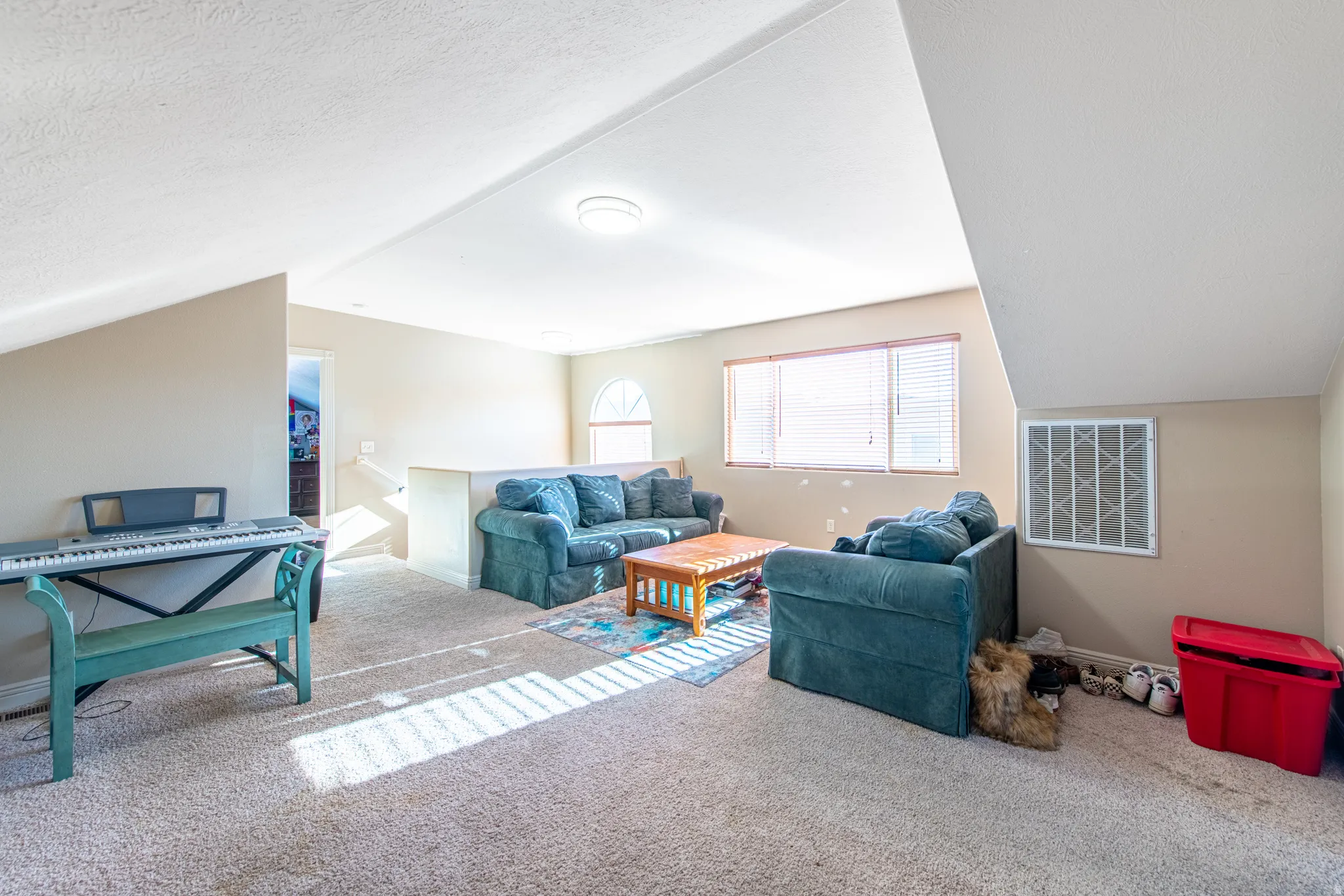 Carpeted room with sloped ceilings, multiple windows, and a built-in half wall