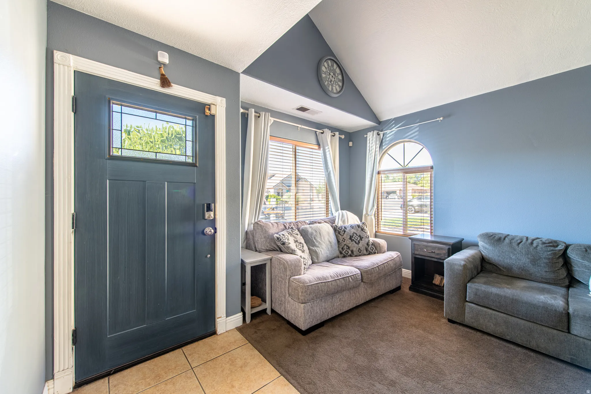 Vaulted ceiling with an accent wall, tiled entry, and transom window above the entry door