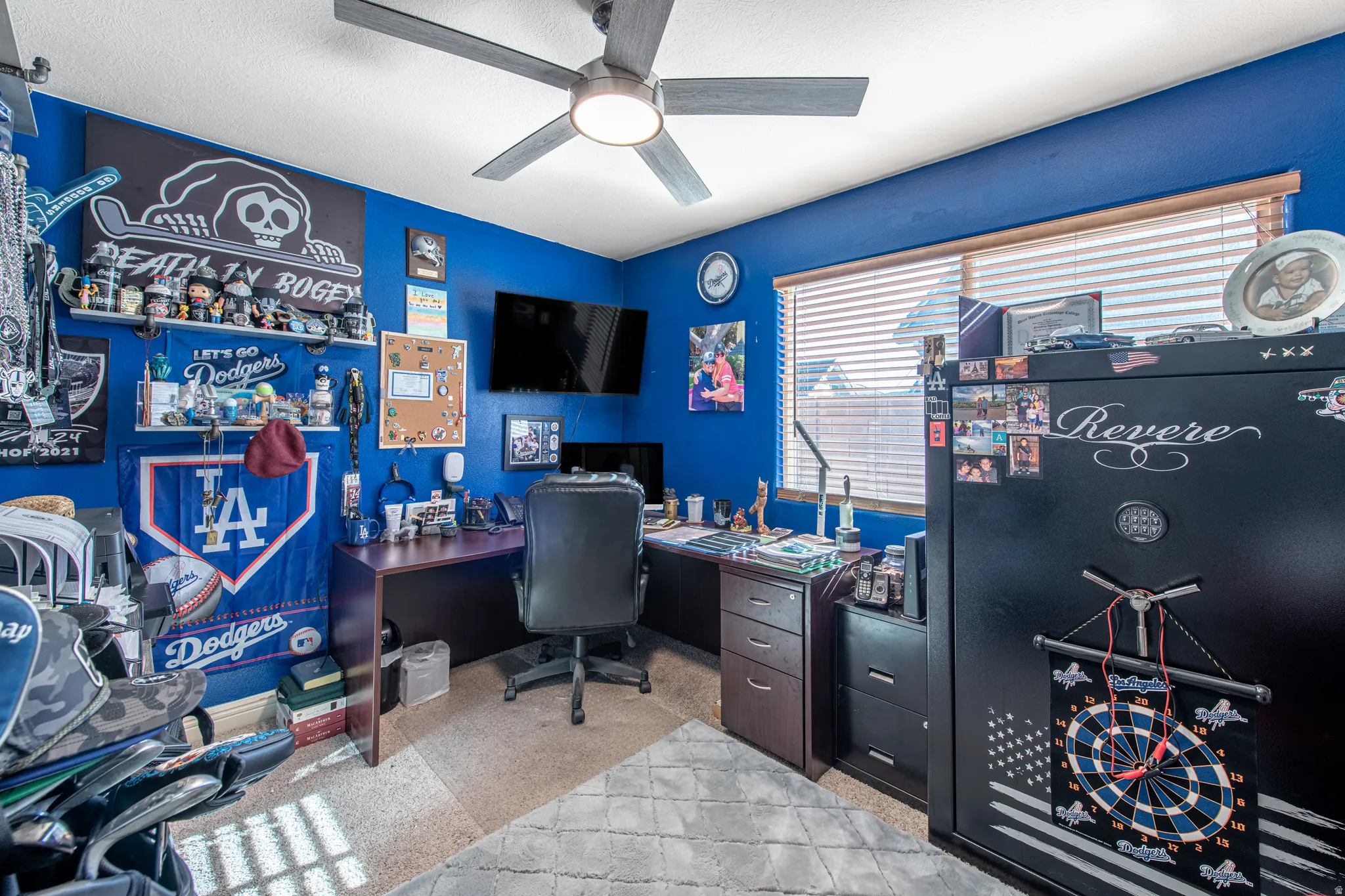 Ceiling fan with integrated lighting, wall-mounted shelving, wood-finish blinds, and a built-in desk area