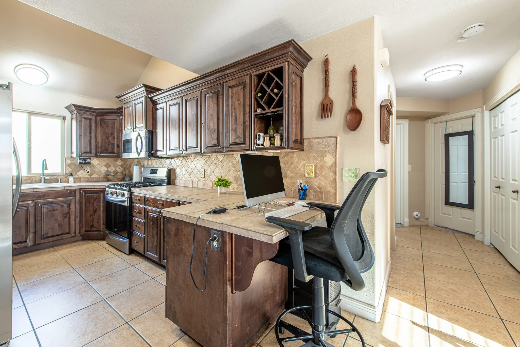 Kitchen featuring wood cabinetry, stainless steel appliances, tile flooring, and a tile backsplash