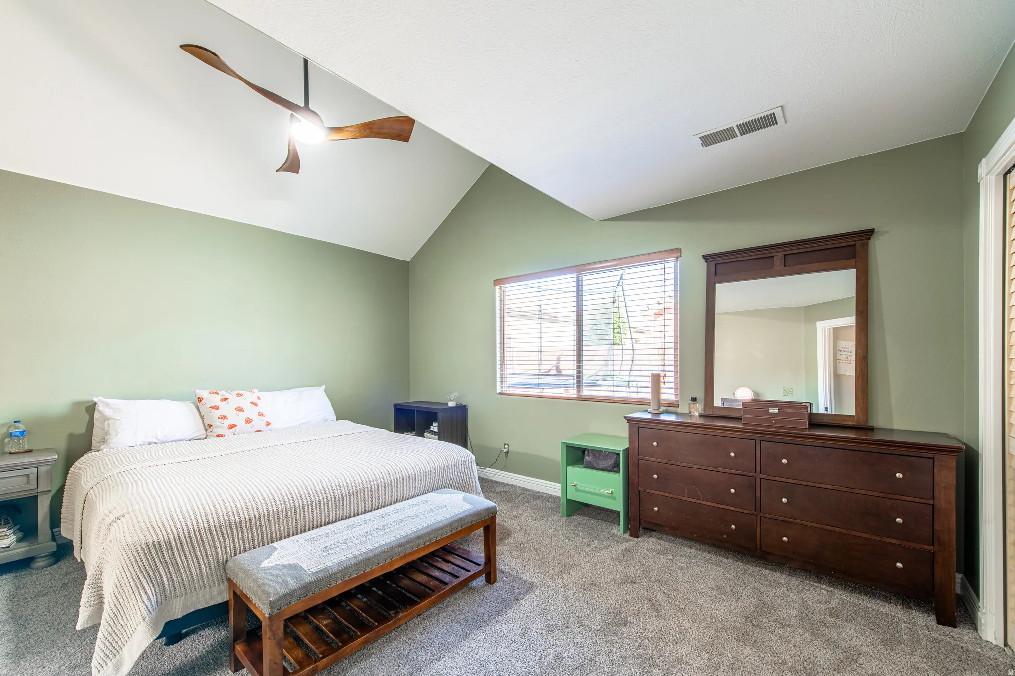 Vaulted ceiling with an attached ceiling fan, wall-to-wall carpeting, and a window with blinds