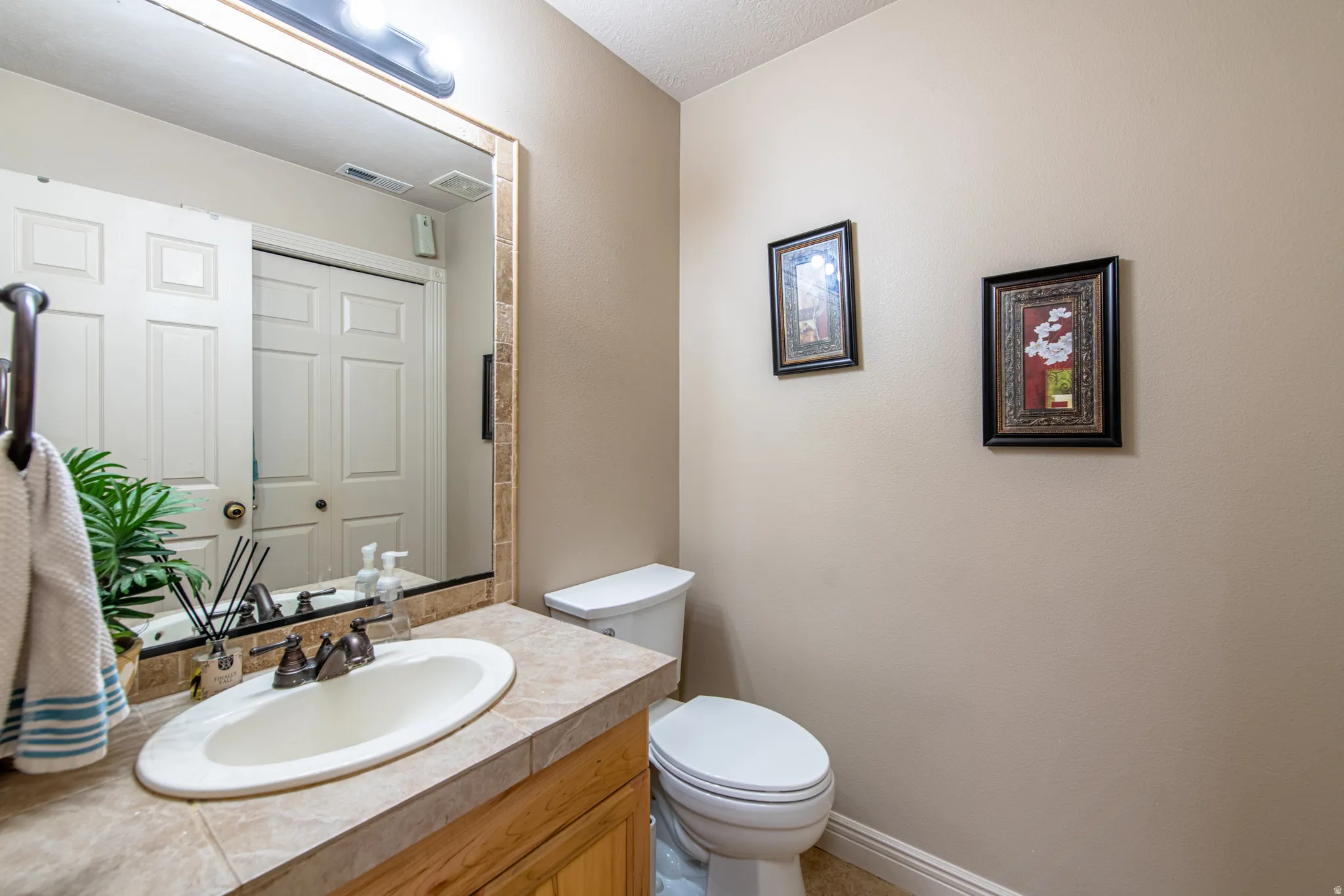 Vanity with an integrated oval sink, countertop with tile finish, and a wood-finish cabinet