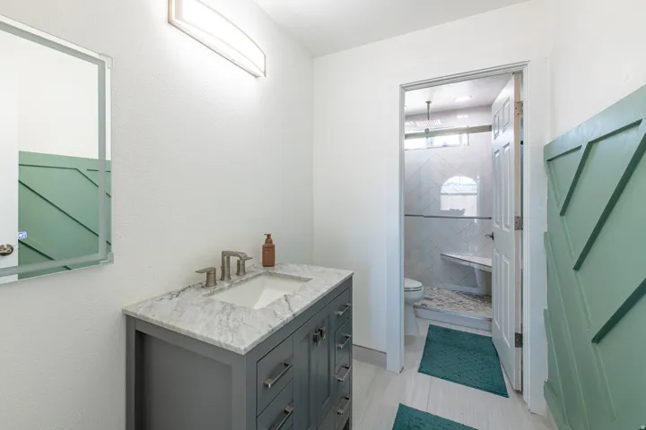 Contemporary vanity with a rectangular undermount sink, stone countertop, and brushed nickel faucet