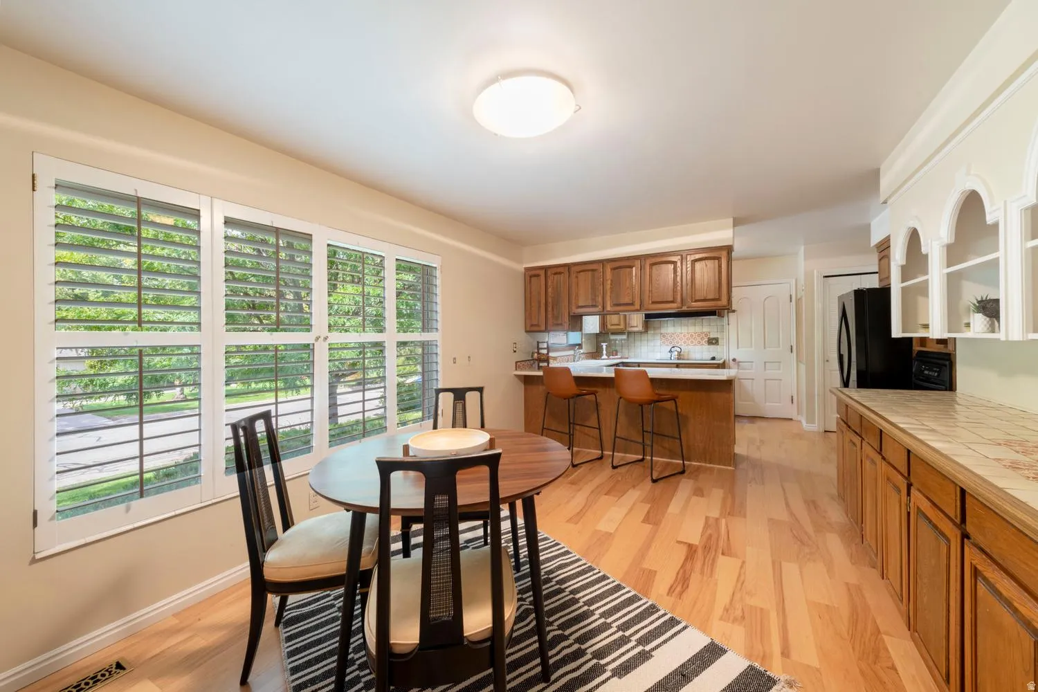 Wood-finish flooring throughout, plantation shutters, overhead flush-mount lighting, and solid wood cabinetry