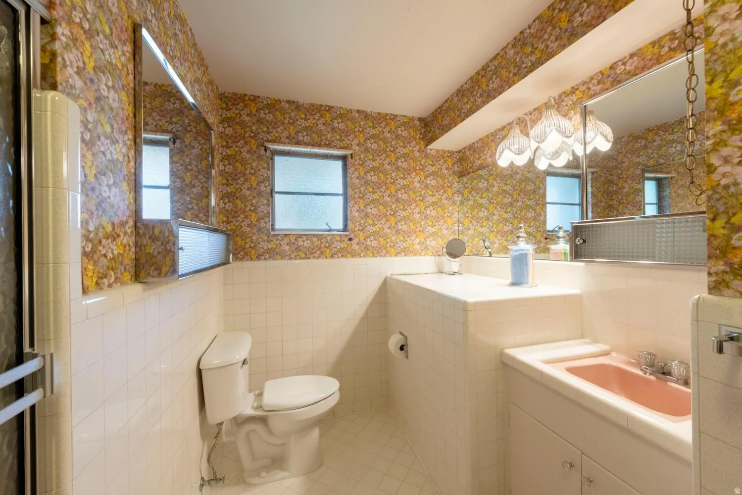 Built-in vanity with integrated sink, wall-mounted mirror, and overhead decorative lighting