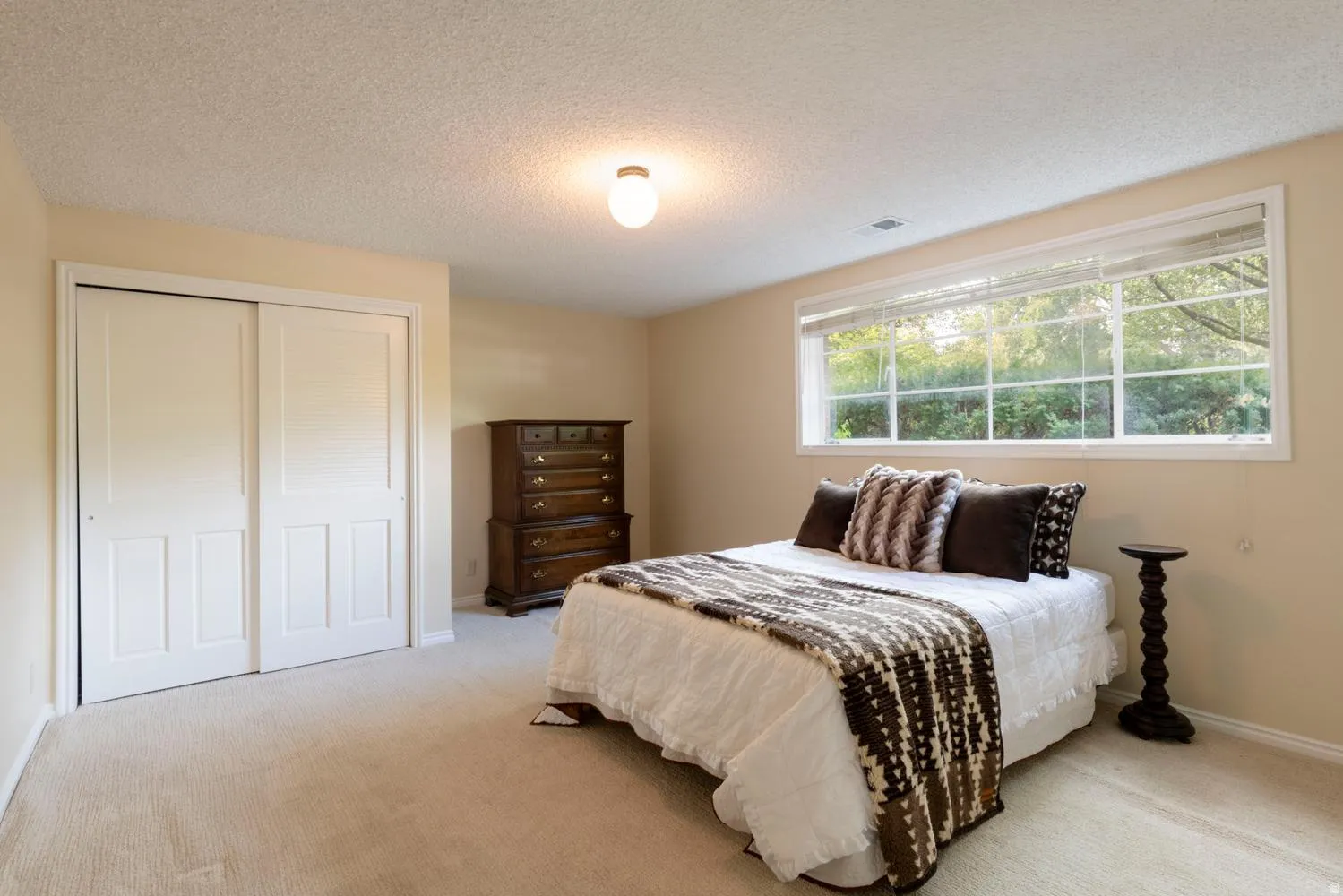 Wall-to-wall carpeting, large window with natural light, and sliding closet doors