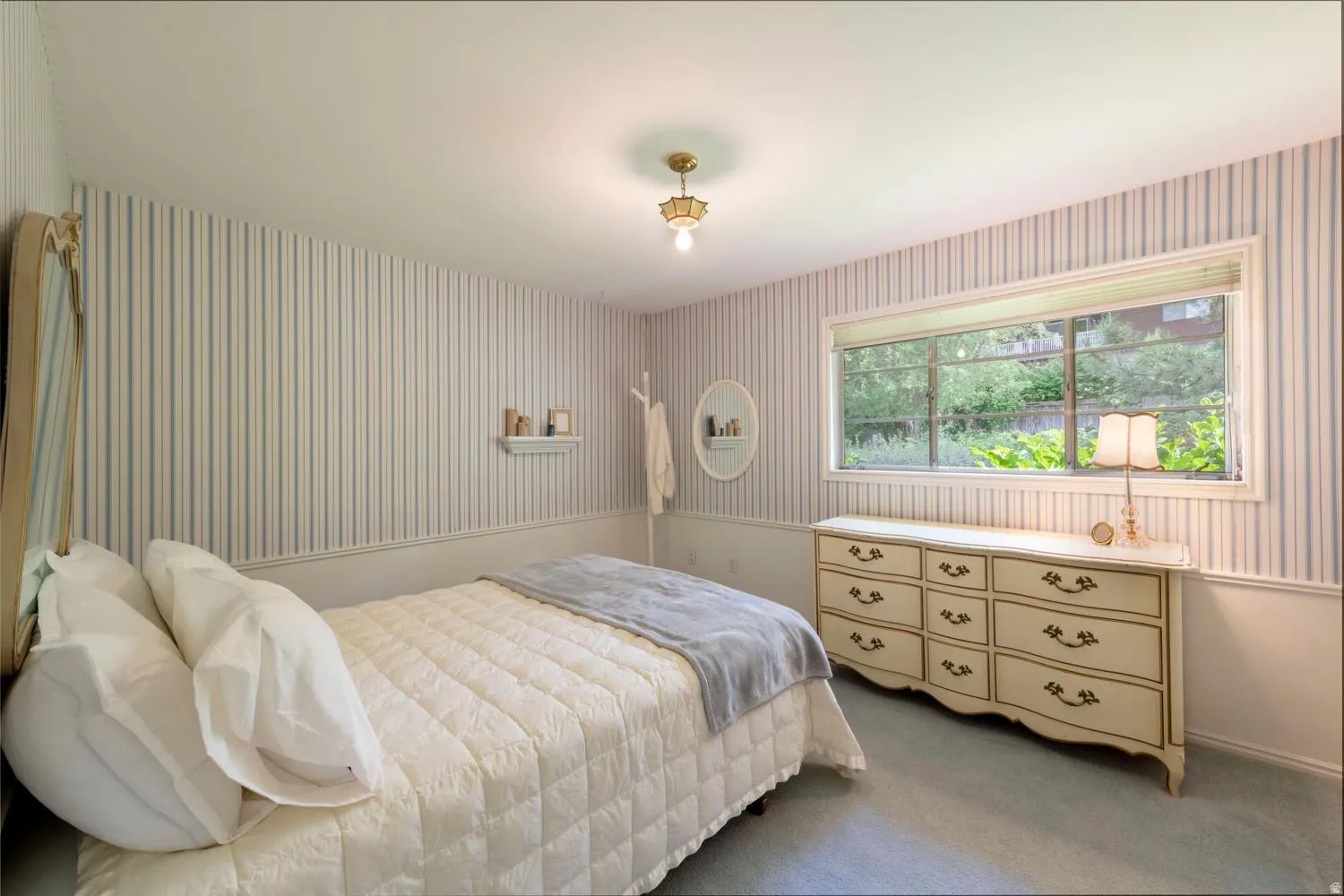Striped wallpaper, wainscoting, and a ceiling-mounted light fixture