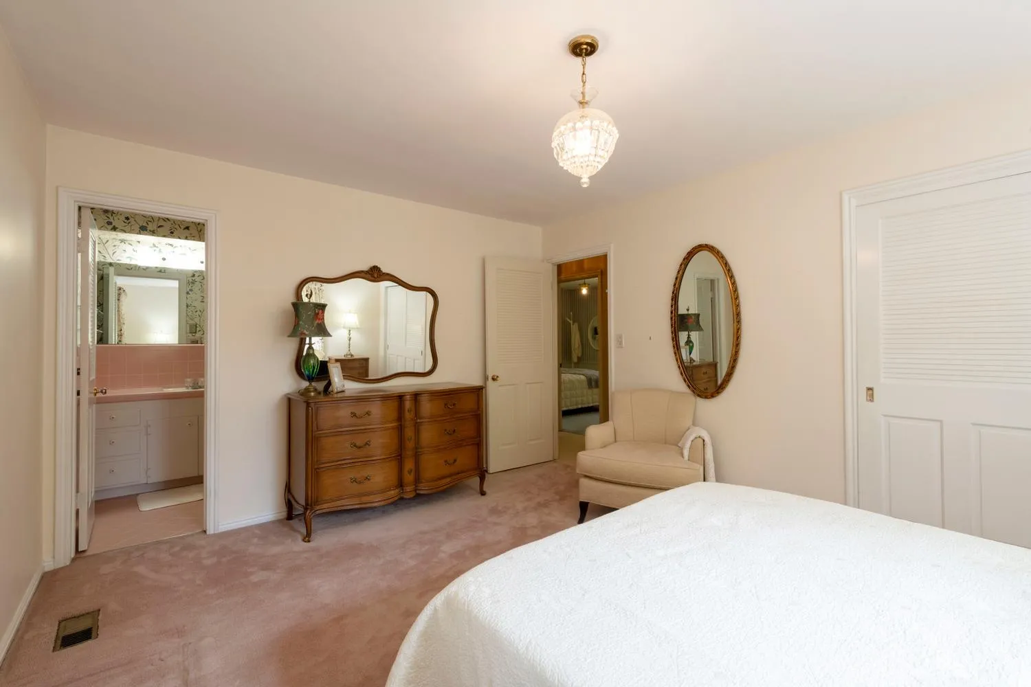 Ceiling-mounted crystal light fixture, neutral wall color, pink carpet flooring, interior doorway, and white interior doors