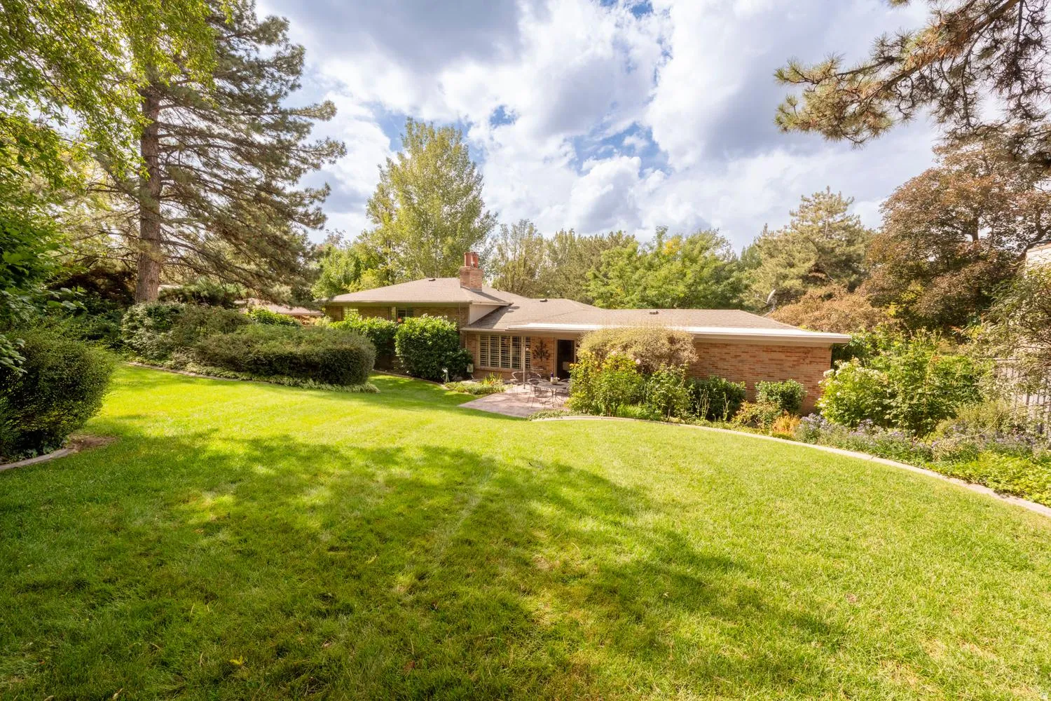 Expansive backyard with a large lawn area, mature trees, and landscaping