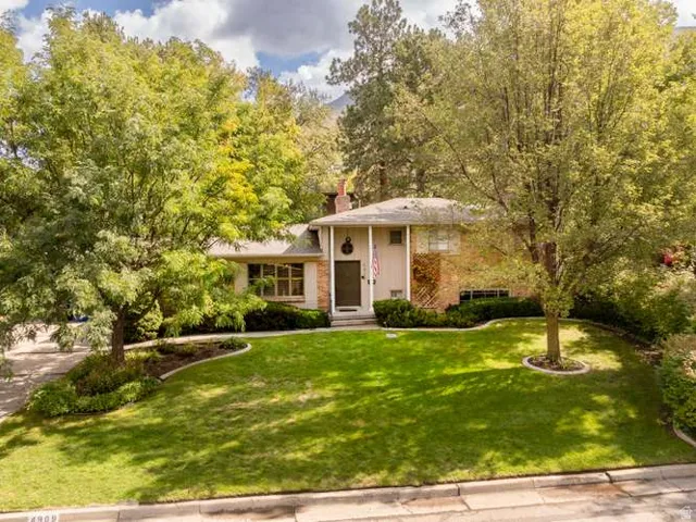 Expansive front lawn with mature trees and established landscaping