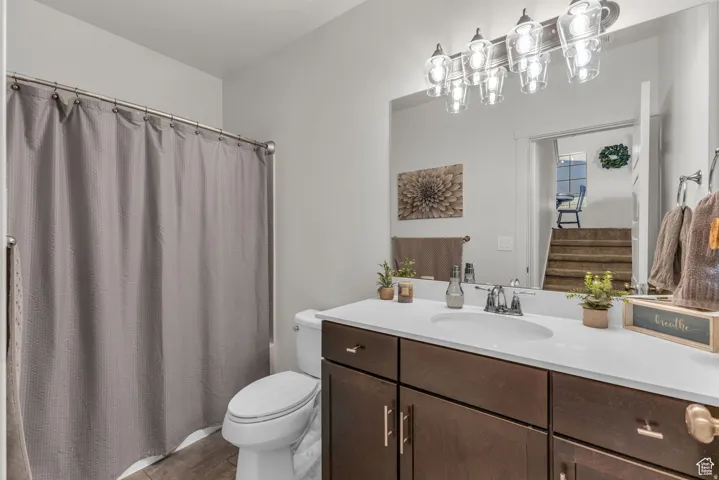 Vanity with a white countertop and wood-finish cabinetry, featuring a single basin and chrome faucet