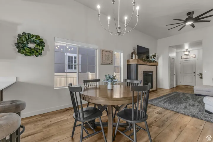 Wood-finish flooring throughout, a modern fireplace with a wood mantle, a contemporary chandelier, and a black ceiling fan