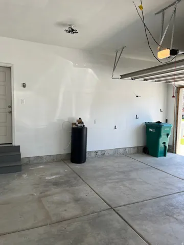 Concrete slab flooring, white painted walls, and ceiling-mounted lighting