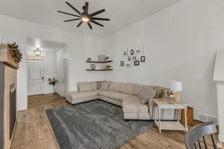 Vaulted ceiling with a contemporary ceiling fan, wood-finish flooring, built-in fireplace, and corner shelving
