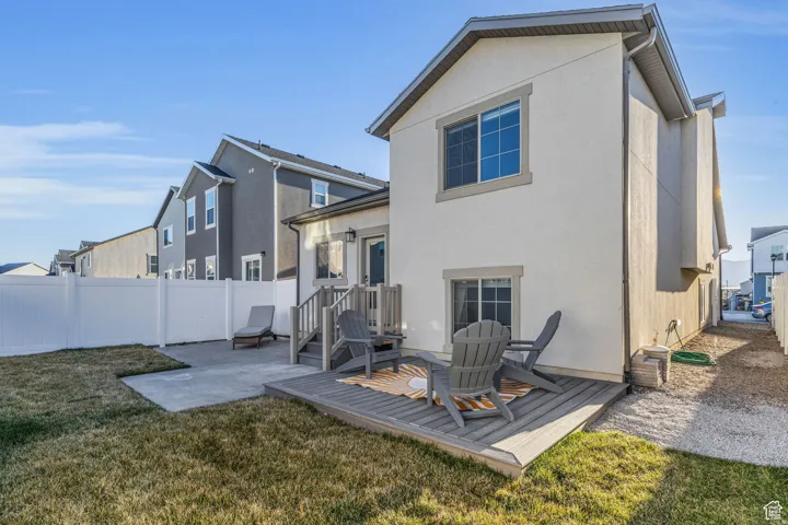 Spacious backyard featuring a composite deck, concrete patio, and a white privacy fence