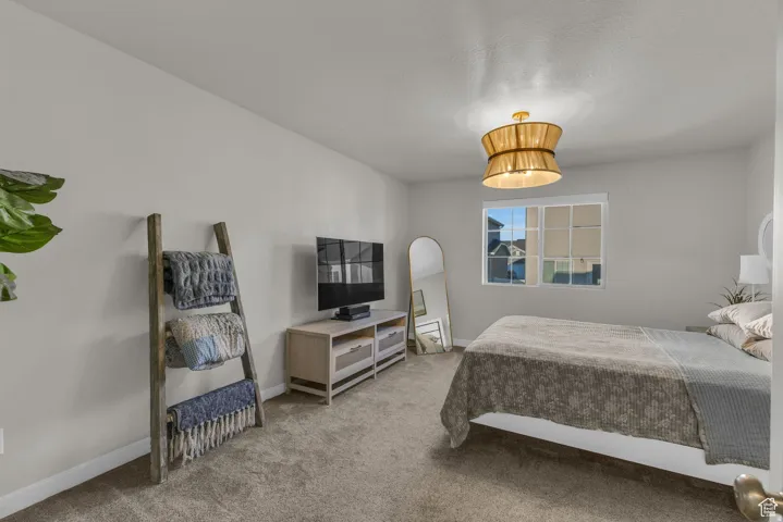 Textured carpet flooring, white painted walls, multi-pane window, and a drum pendant light fixture