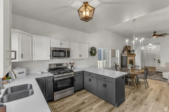 Kitchen featuring two-tone cabinetry, stainless steel appliances, white countertops, and wood-finish flooring