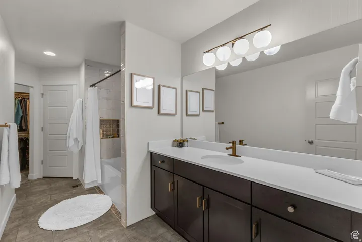 Double vanity with a white countertop and brass-finish fixtures, wood-finish cabinetry, and a full-width mirror