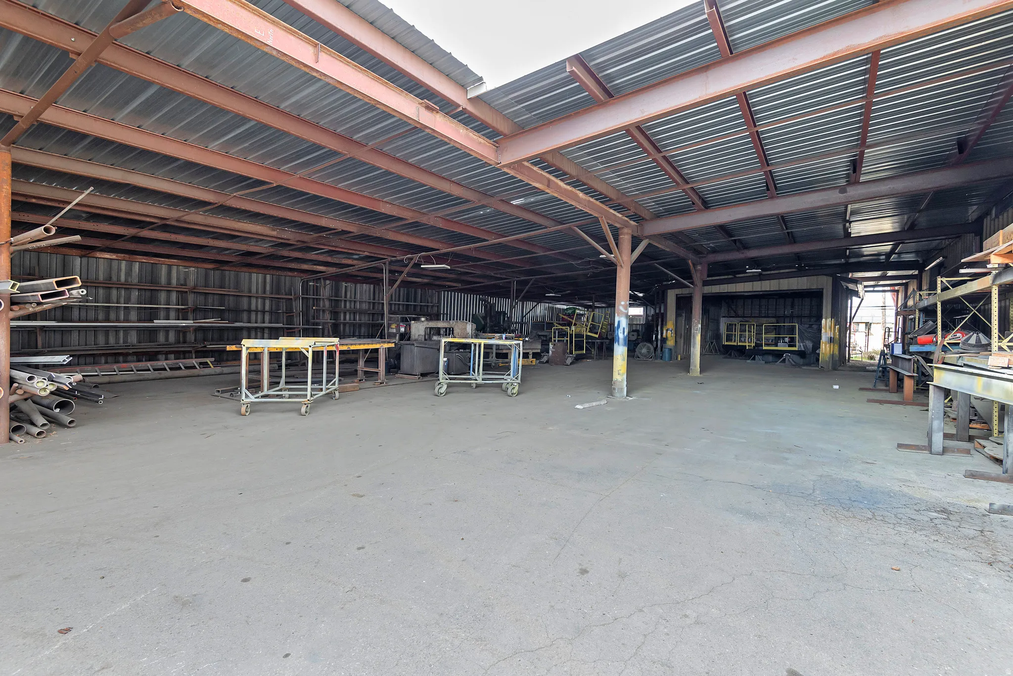 Open-air warehouse featuring a corrugated metal roof and exposed steel beam construction