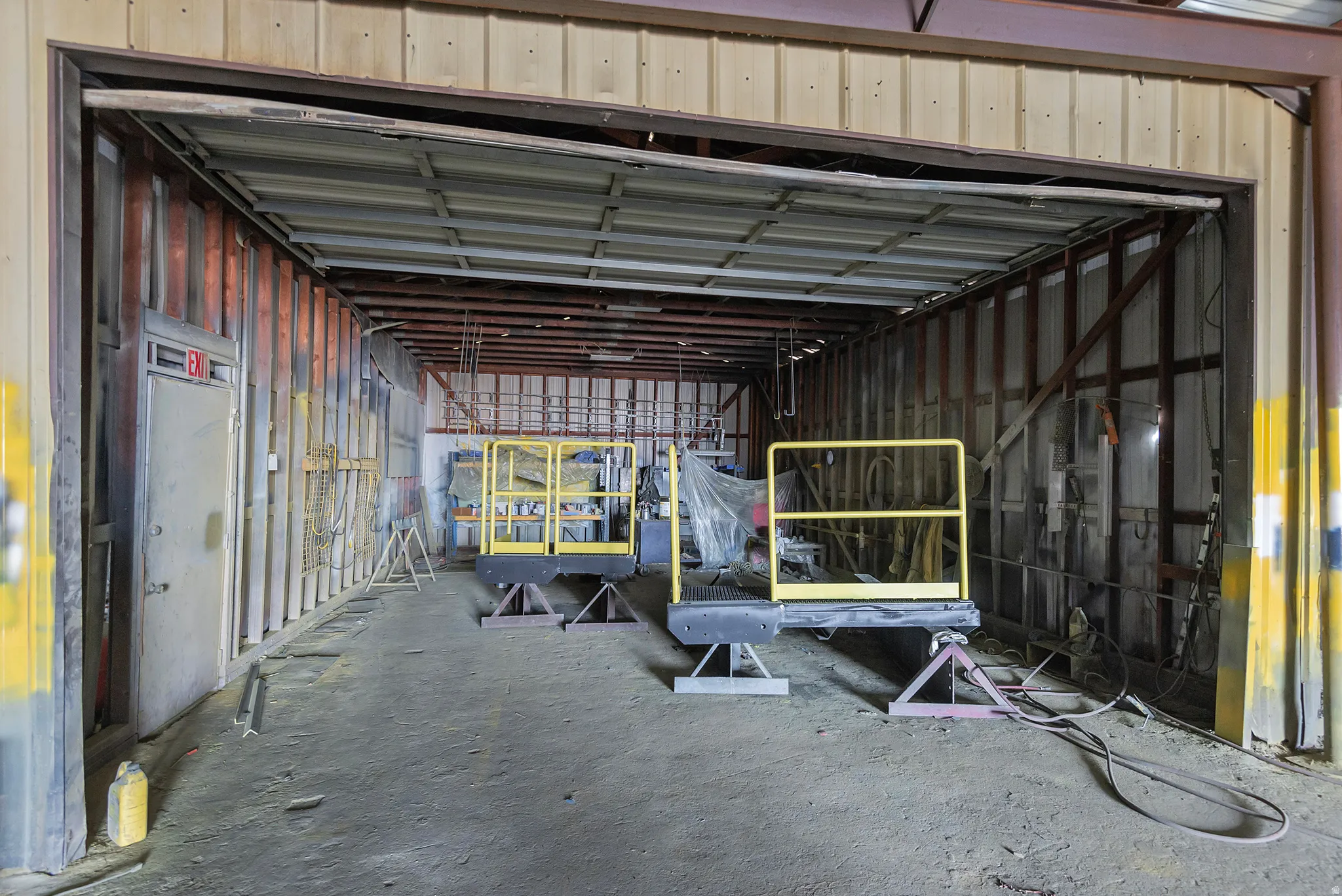 Open warehouse space with a concrete floor, metal beam ceiling, and exposed wall studs