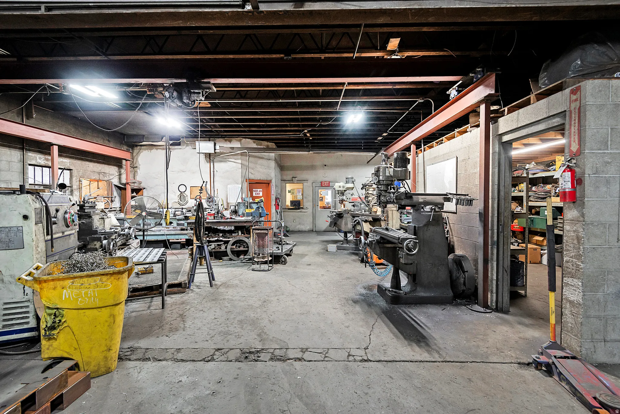 Industrial space featuring concrete flooring, exposed ceiling beams, and overhead lighting