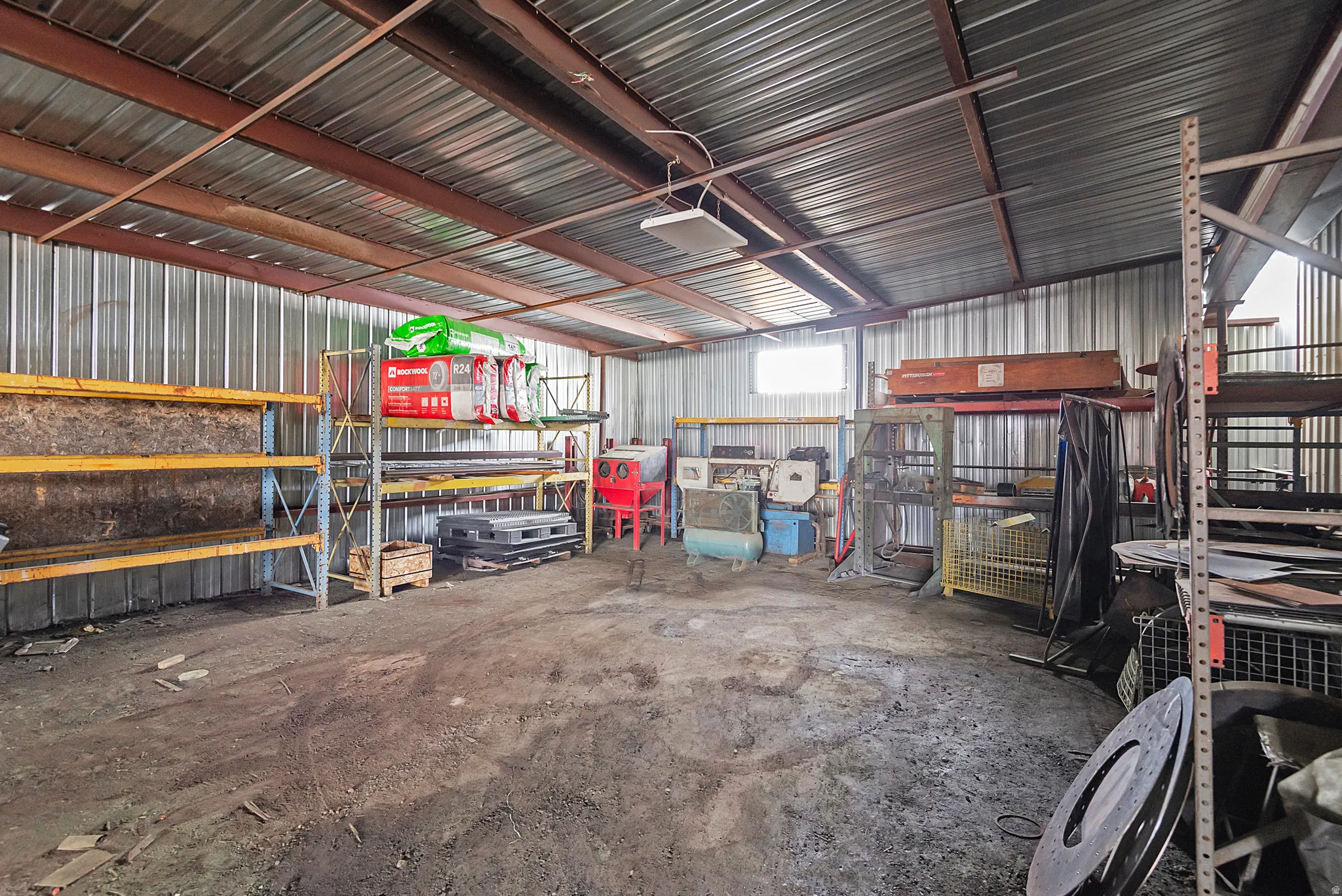 Spacious interior with a corrugated metal roof, exposed steel beams, and concrete flooring