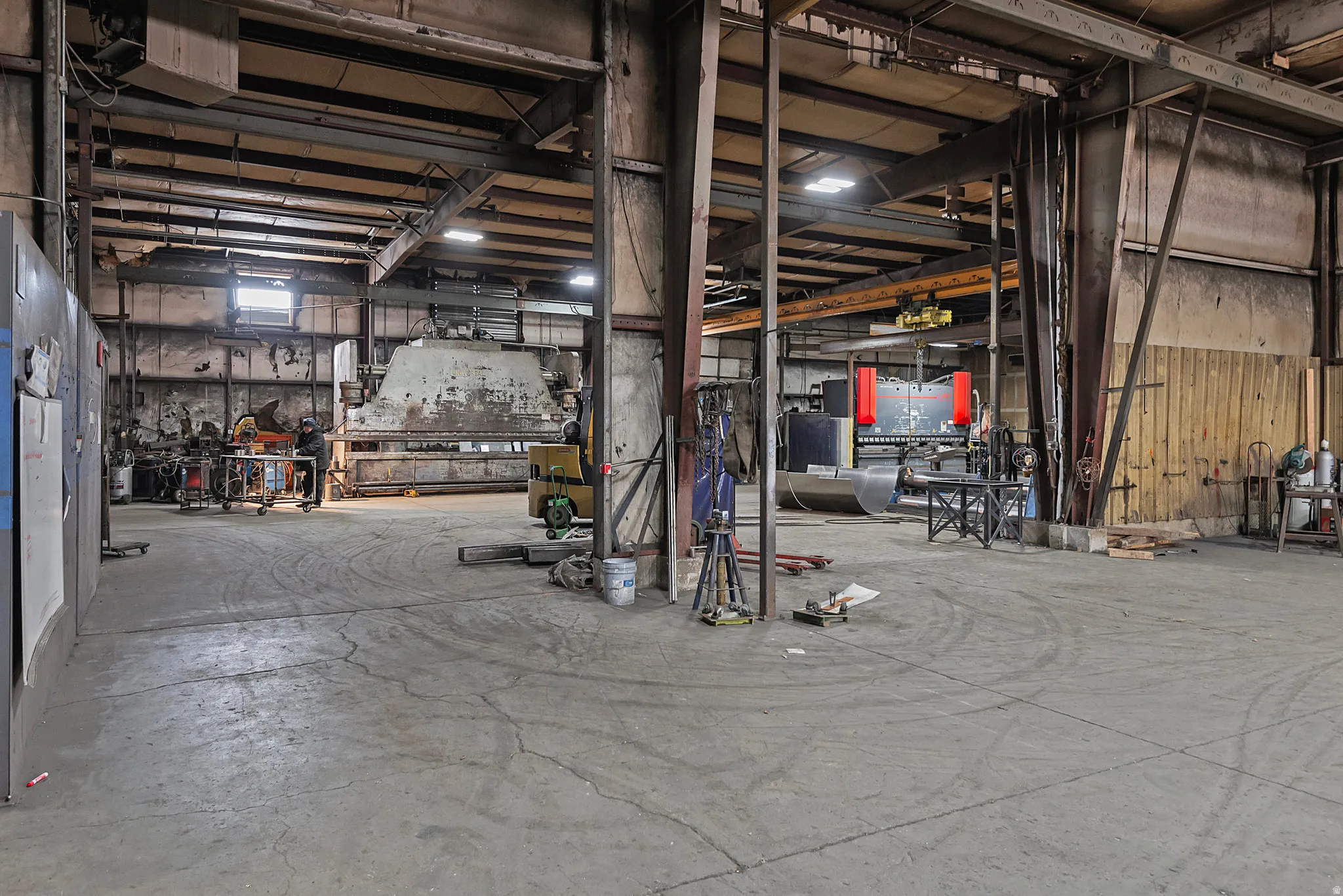 Large industrial space featuring exposed structural beams, concrete flooring, and high ceilings