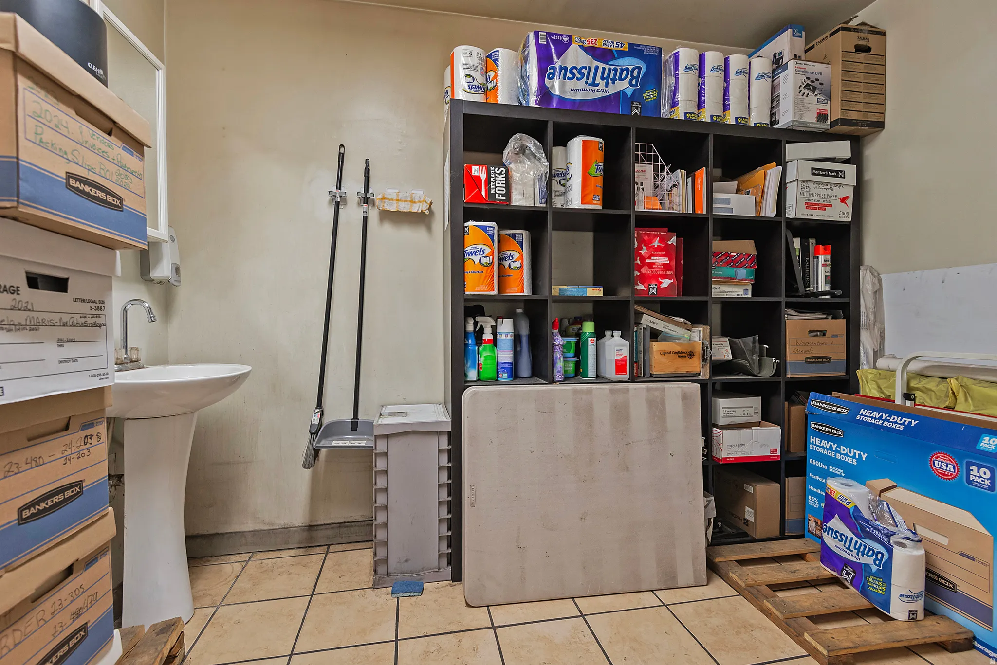 Pedestal sink, tile flooring, and wall-mounted shelving