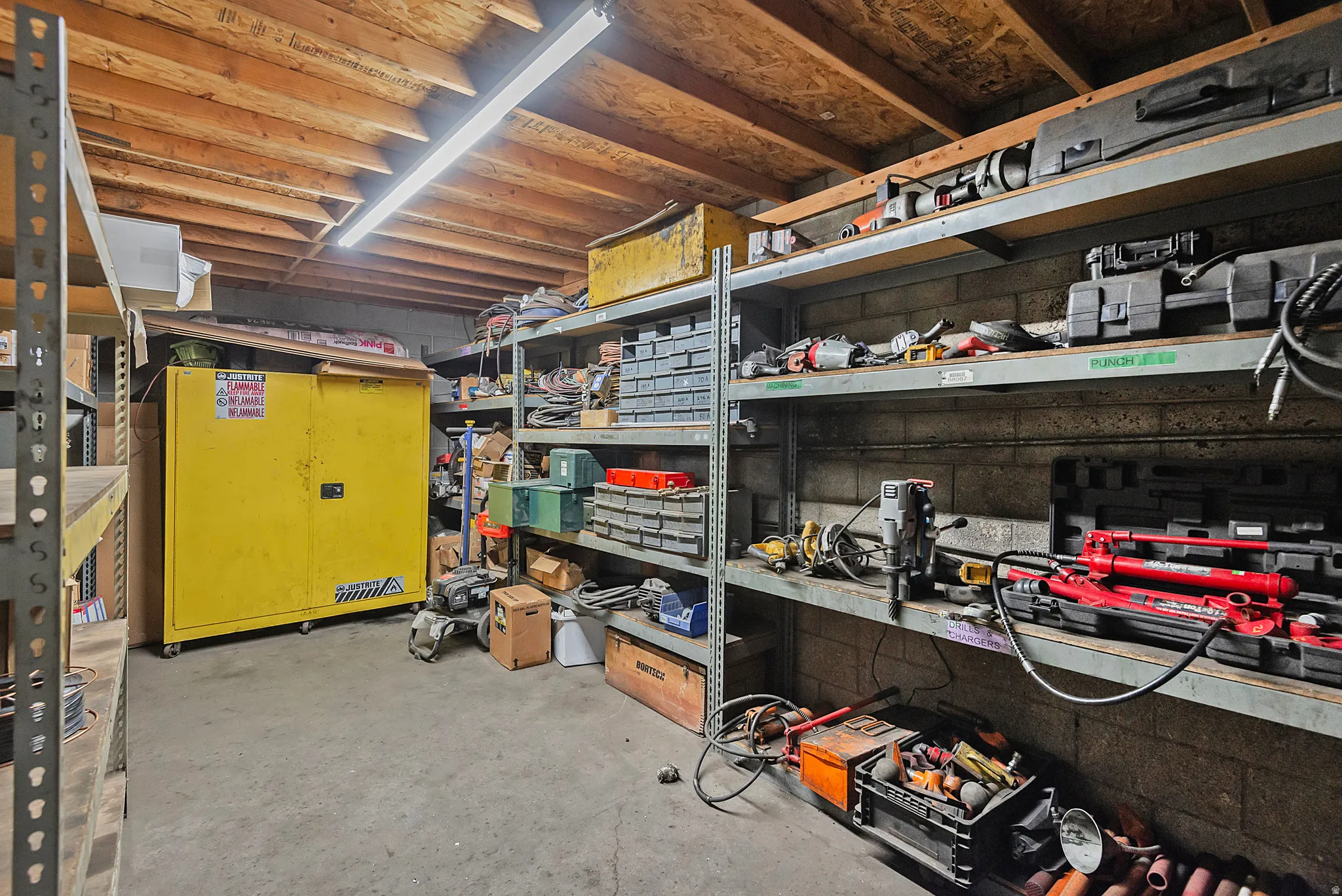 Exposed wood ceiling joists, concrete block walls, and fluorescent strip lighting