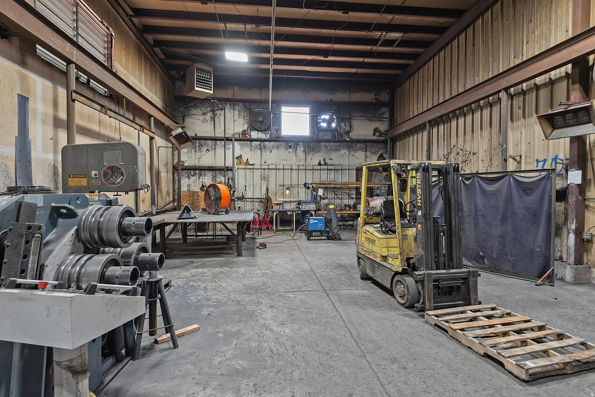 Industrial warehouse space featuring exposed structural beams, high ceilings, and concrete flooring