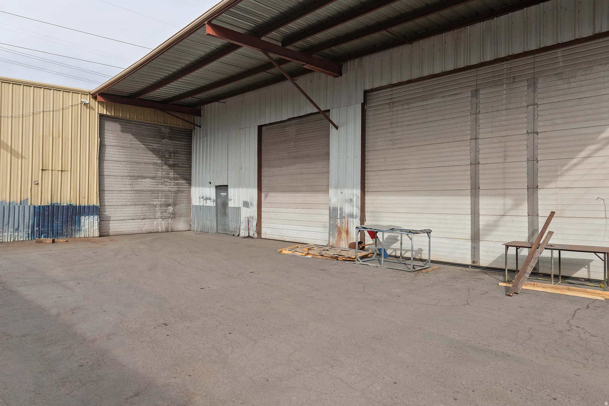 Metal construction with multiple roll-up doors, covered exterior areas, and a concrete lot