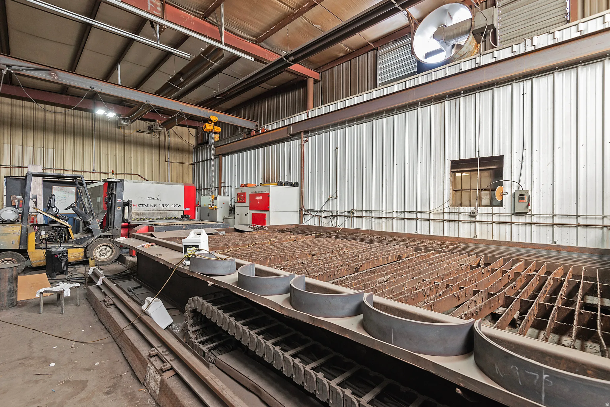 Industrial space with corrugated metal walls, exposed structural beams, and integrated overhead lighting