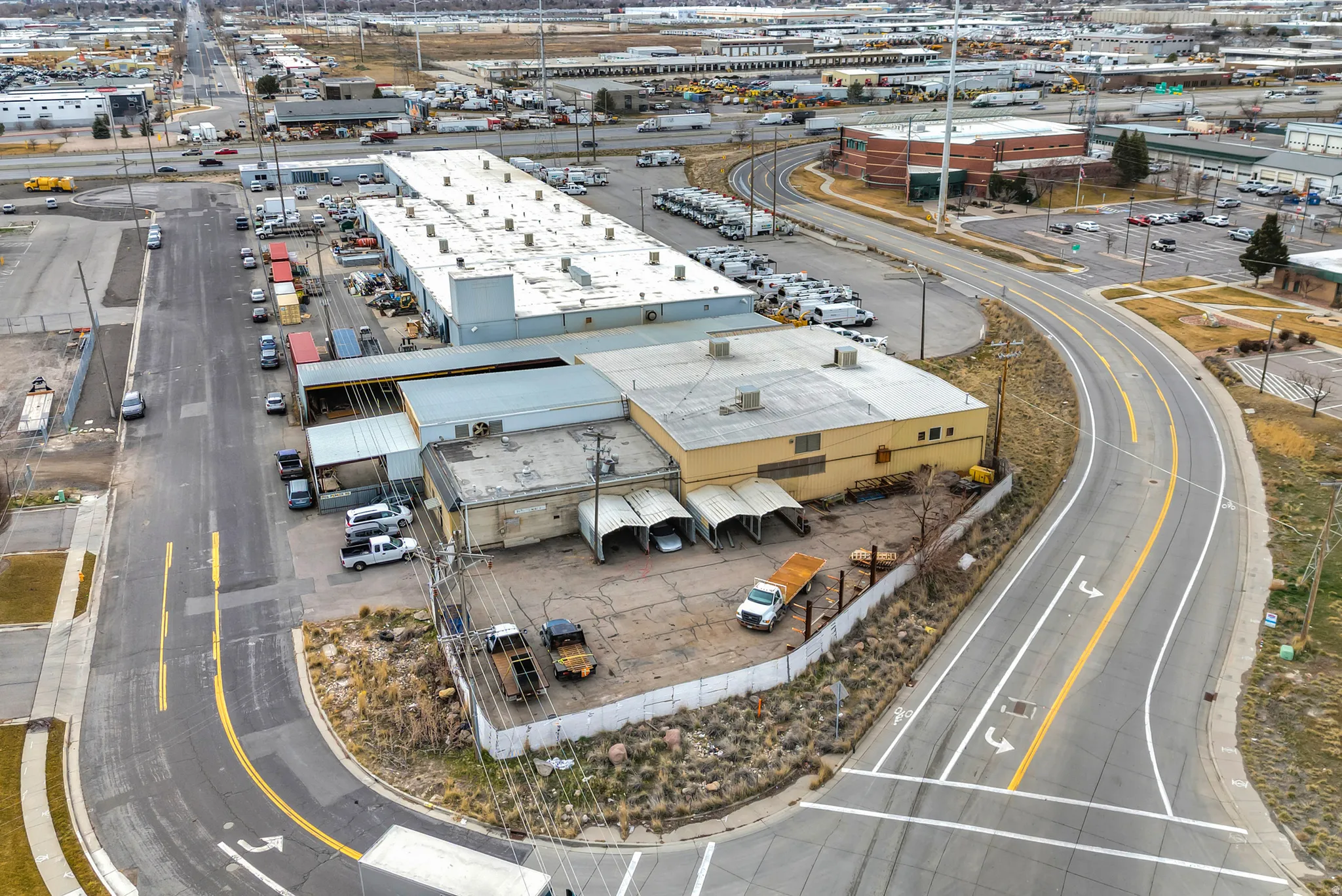 Industrial property featuring a main building with multiple bays, adjacent parking area, and direct road access